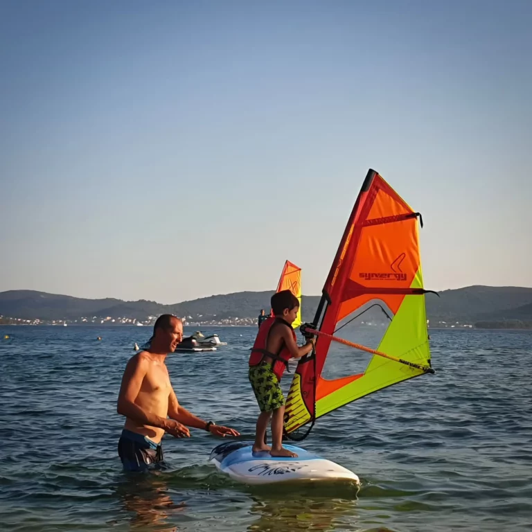 Otac i dijete uče jedriti na dasci