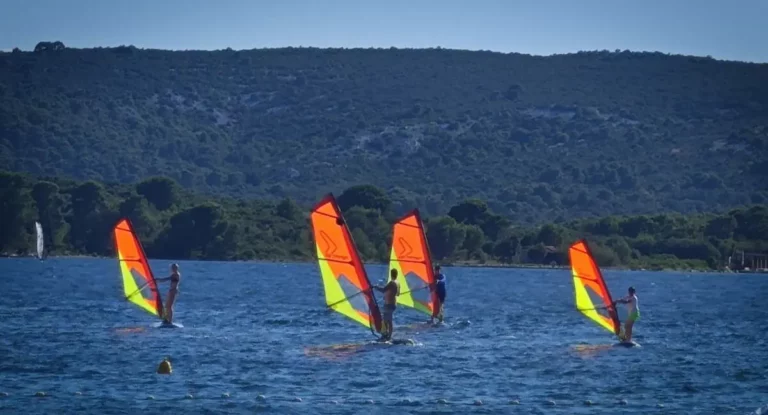 Četiri surfera na dasci s jedrima na moru